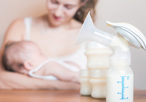Woman holding baby with breast pumps on nearby table